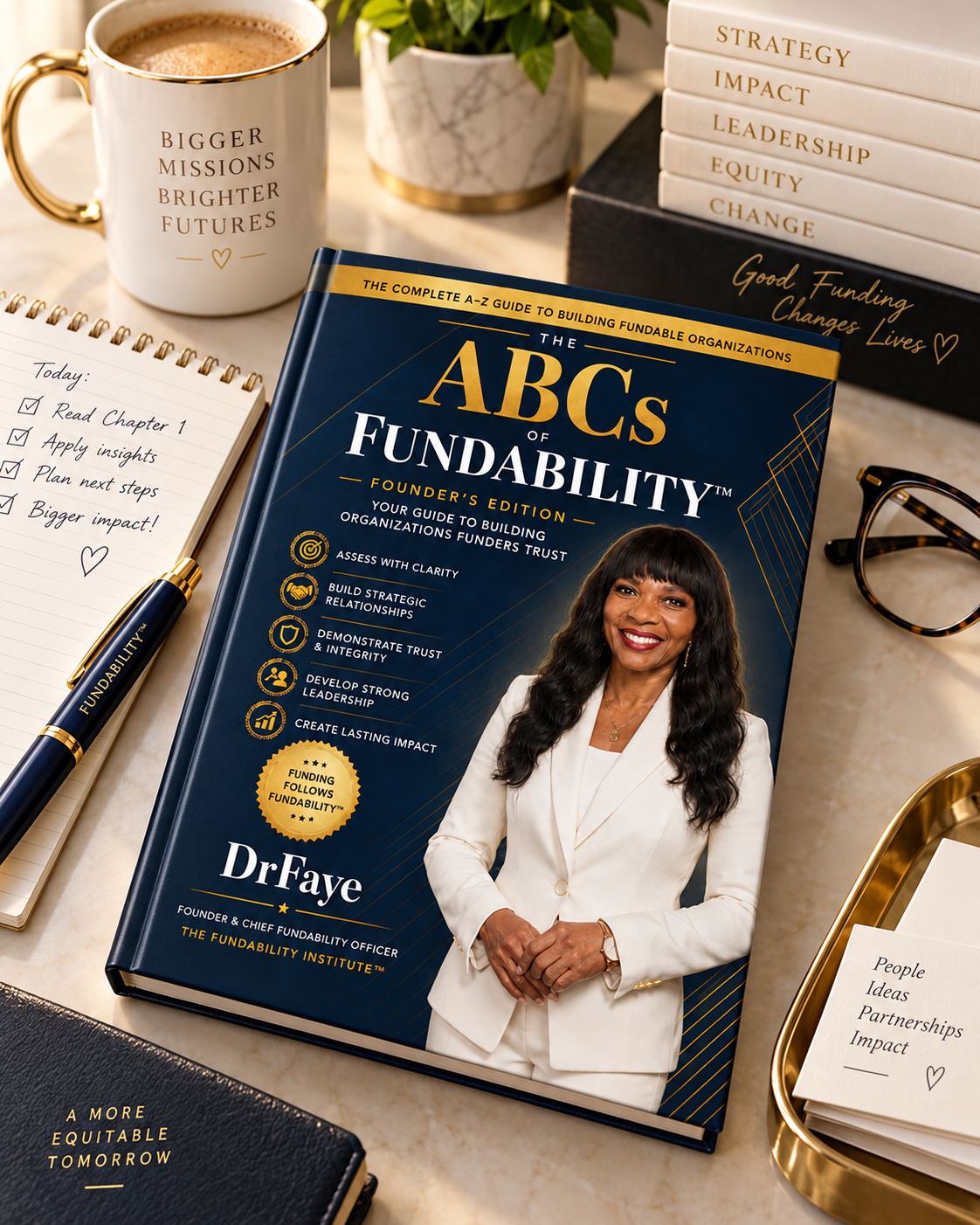 The ABCs of Fundability workbook on a desk beside a notebook, pen, and coffee